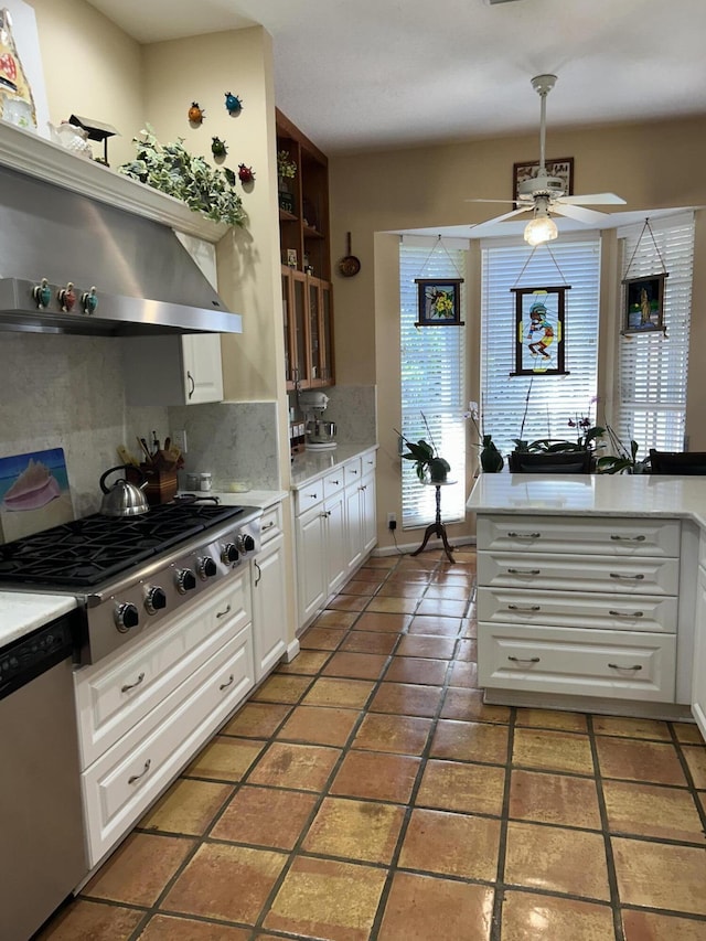 kitchen with appliances with stainless steel finishes, tasteful backsplash, ceiling fan, dark tile patterned flooring, and white cabinetry