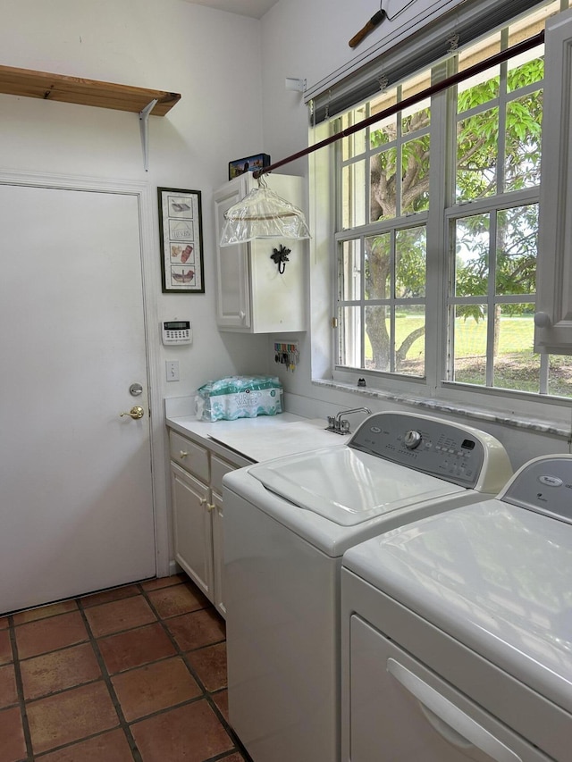 laundry area featuring washing machine and dryer, a wealth of natural light, cabinets, and dark tile patterned flooring