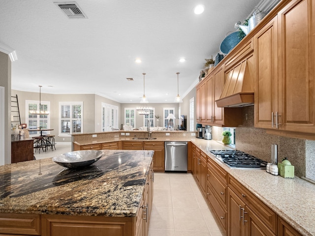 kitchen featuring hanging light fixtures, appliances with stainless steel finishes, crown molding, a kitchen island, and custom exhaust hood