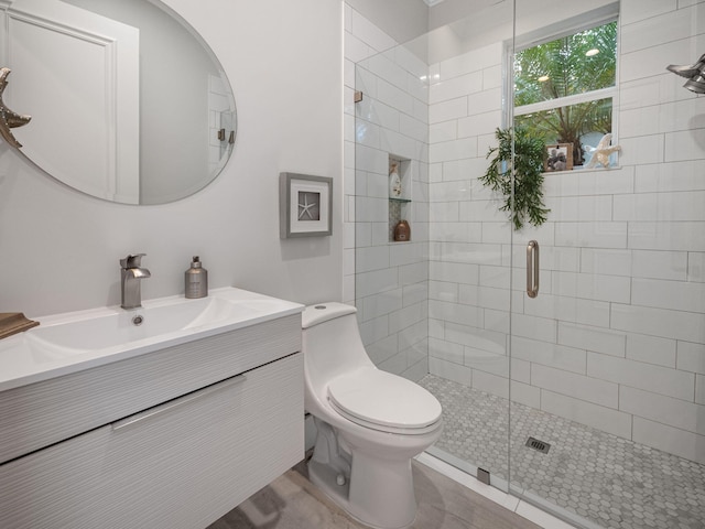 bathroom featuring vanity, toilet, and a shower with door