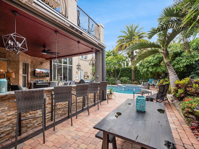 view of patio / terrace with exterior bar, a swimming pool with hot tub, a balcony, and ceiling fan