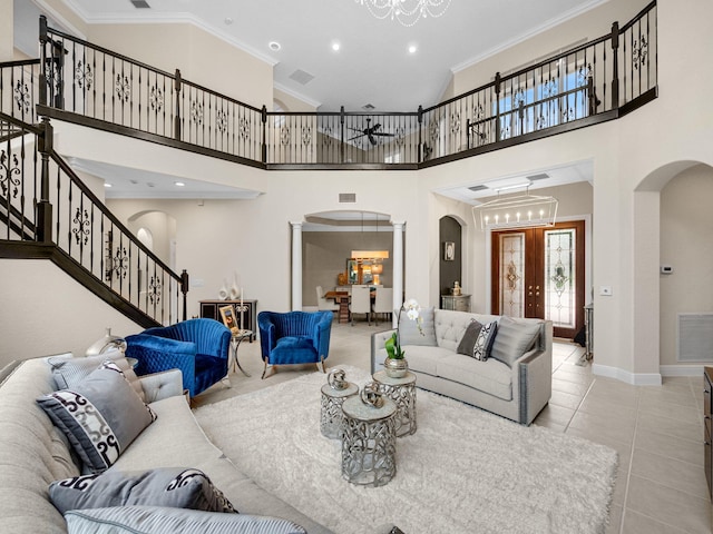 living room featuring ornate columns, ornamental molding, a notable chandelier, a high ceiling, and light tile patterned flooring