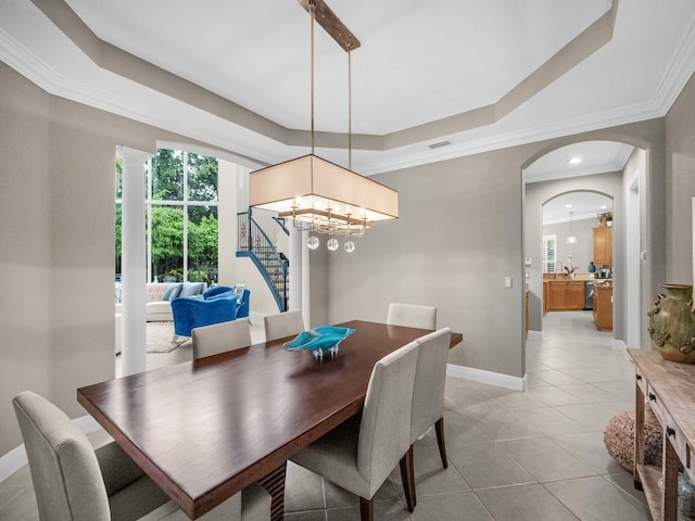 dining area with a tray ceiling, tile patterned floors, ornamental molding, and a notable chandelier