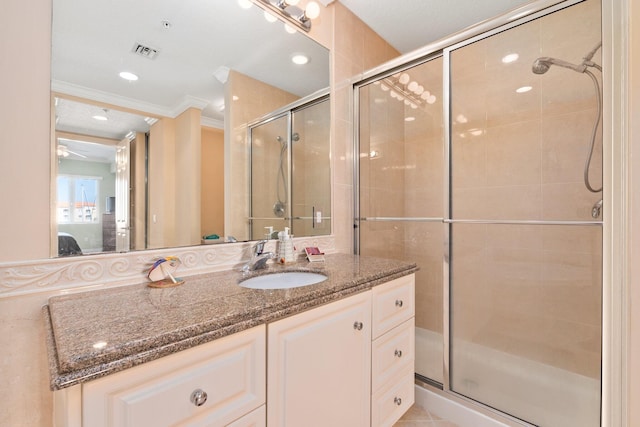 bathroom with vanity, crown molding, ceiling fan, and a shower with shower door