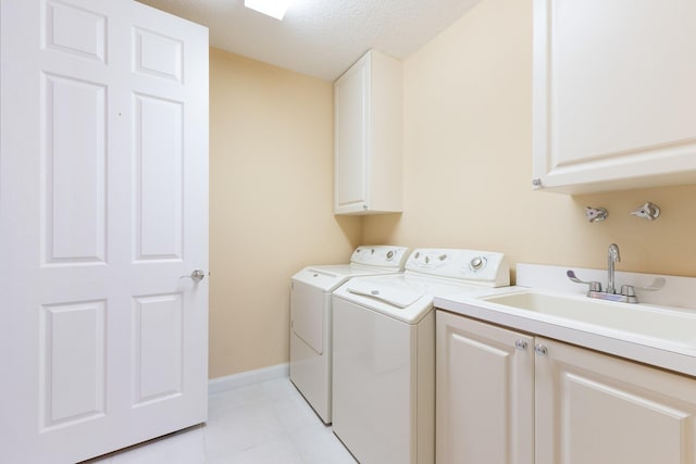 clothes washing area with cabinets, sink, separate washer and dryer, a textured ceiling, and light tile patterned flooring