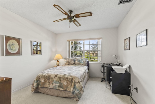 bedroom with ceiling fan, light colored carpet, and a textured ceiling