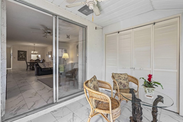 sunroom featuring ceiling fan with notable chandelier