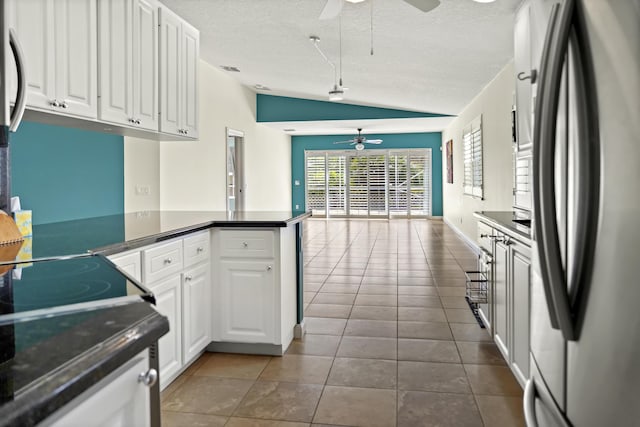 kitchen featuring lofted ceiling, stainless steel refrigerator, kitchen peninsula, ceiling fan, and white cabinets