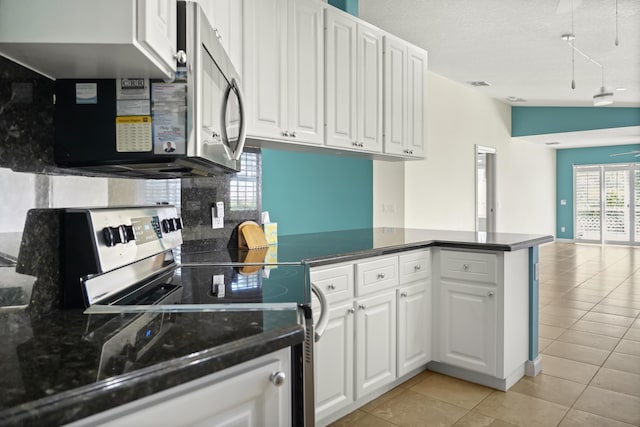 kitchen featuring white cabinetry, vaulted ceiling, light tile patterned floors, appliances with stainless steel finishes, and kitchen peninsula