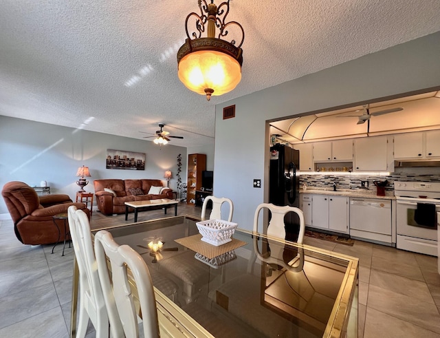 tiled dining room with ceiling fan and a textured ceiling