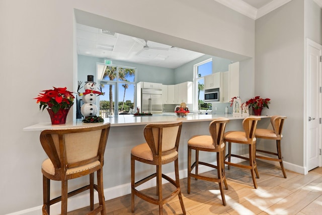 kitchen featuring kitchen peninsula, a wealth of natural light, white cabinets, and appliances with stainless steel finishes