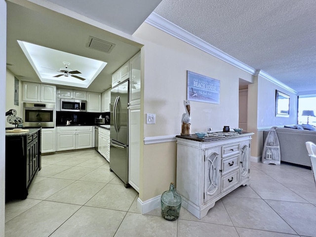 kitchen with ceiling fan, crown molding, a textured ceiling, light tile patterned floors, and appliances with stainless steel finishes