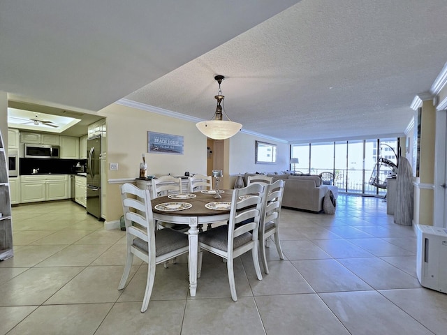 tiled dining area featuring expansive windows, crown molding, ceiling fan, and a textured ceiling