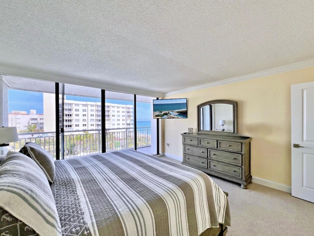 carpeted bedroom featuring access to exterior, a wall of windows, a textured ceiling, and ornamental molding