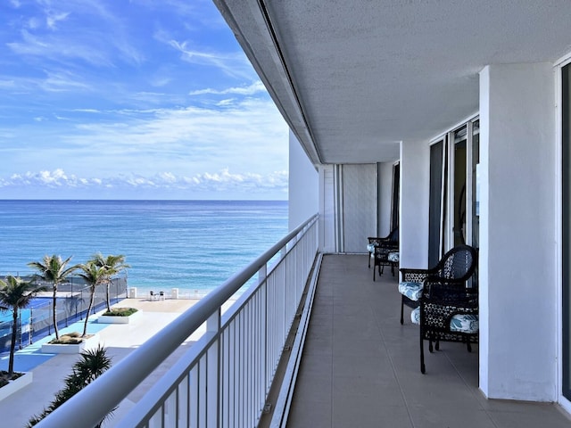 balcony featuring a water view and a view of the beach