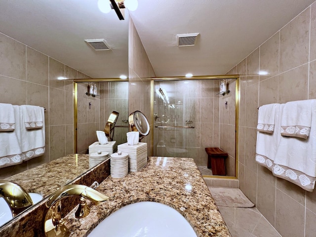 bathroom with vanity, an enclosed shower, and tile walls