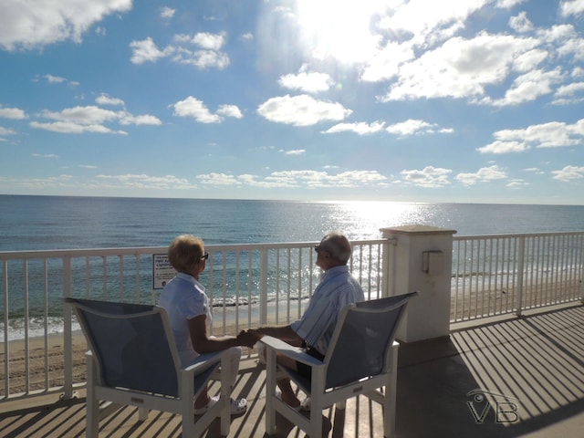 wooden deck with a water view and a view of the beach