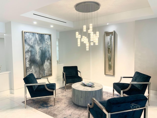 sitting room with a raised ceiling and a chandelier