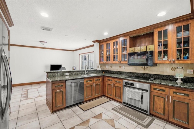 kitchen featuring dark stone countertops, sink, ornamental molding, and stainless steel appliances