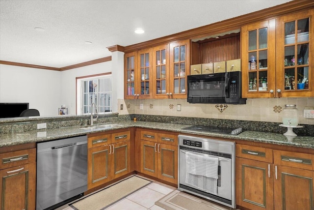 kitchen with appliances with stainless steel finishes, dark stone countertops, and sink