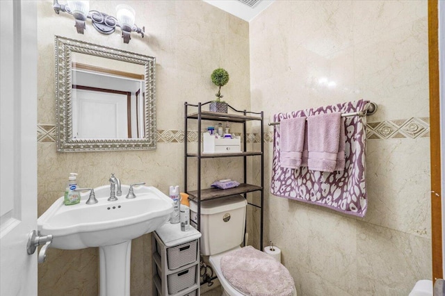 bathroom featuring toilet and tile walls