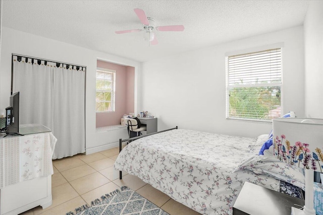 tiled bedroom with ceiling fan and a textured ceiling