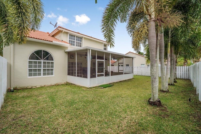 rear view of property featuring a sunroom and a yard