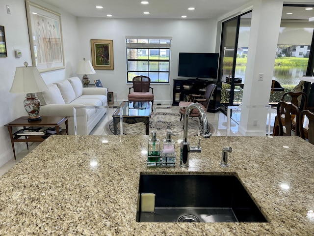 kitchen featuring light stone counters and sink