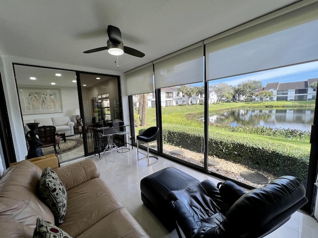 sunroom featuring ceiling fan and a water view