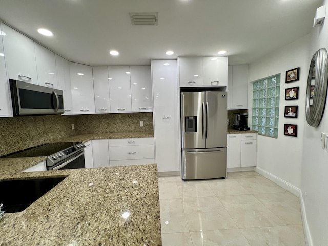 kitchen featuring tasteful backsplash, stainless steel appliances, light tile patterned floors, stone countertops, and white cabinets