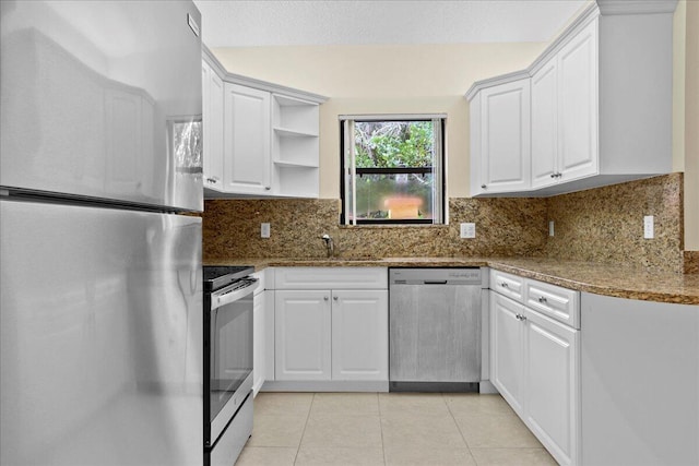 kitchen with backsplash, dark stone countertops, appliances with stainless steel finishes, light tile patterned flooring, and white cabinetry