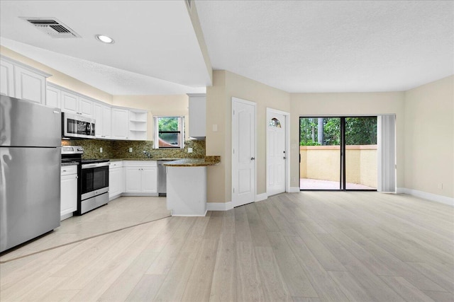 kitchen featuring stainless steel appliances, white cabinetry, tasteful backsplash, and light hardwood / wood-style floors