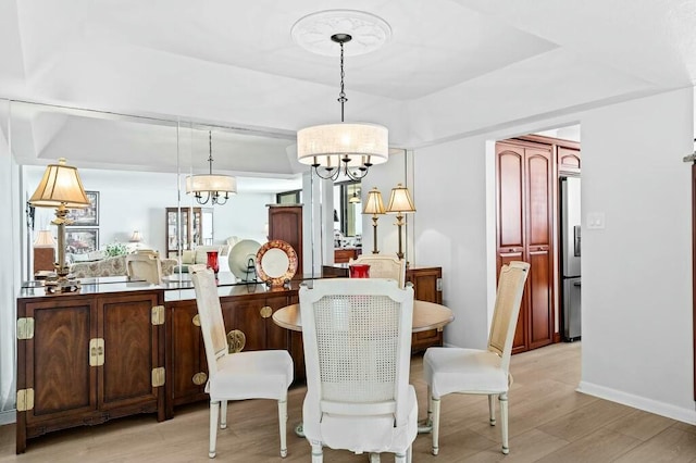 dining space with light hardwood / wood-style floors and a notable chandelier