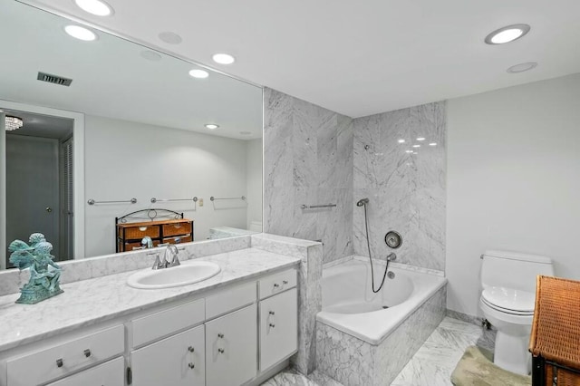 bathroom featuring tiled bath, vanity, and toilet