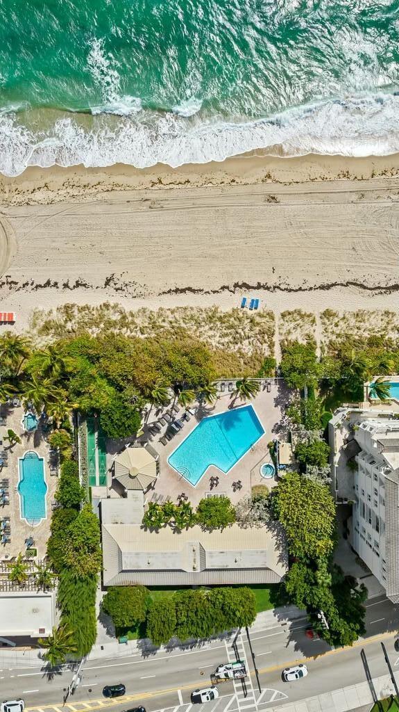 drone / aerial view with a water view and a beach view