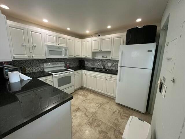 kitchen featuring white appliances, tasteful backsplash, white cabinetry, and sink