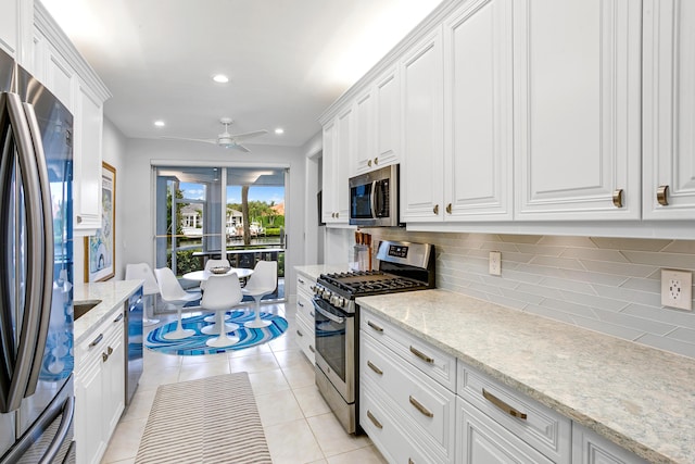 kitchen with ceiling fan, light tile patterned floors, light stone counters, white cabinetry, and stainless steel appliances