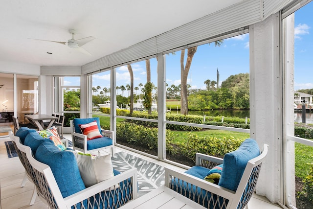 sunroom featuring ceiling fan and a water view