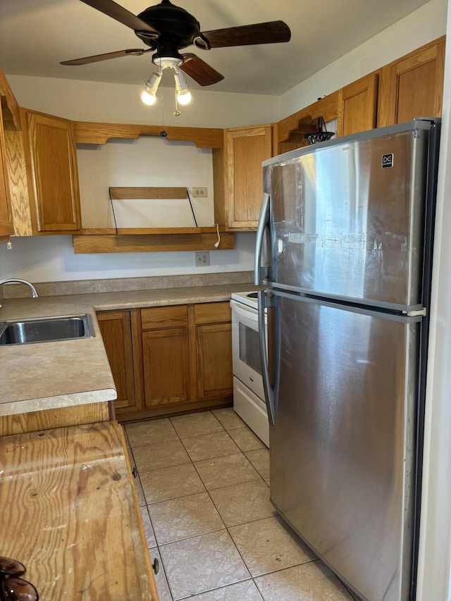 kitchen featuring stainless steel refrigerator, ceiling fan, sink, wood counters, and electric stove