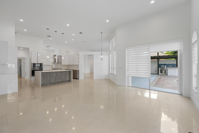 unfurnished living room featuring a towering ceiling and light tile patterned floors