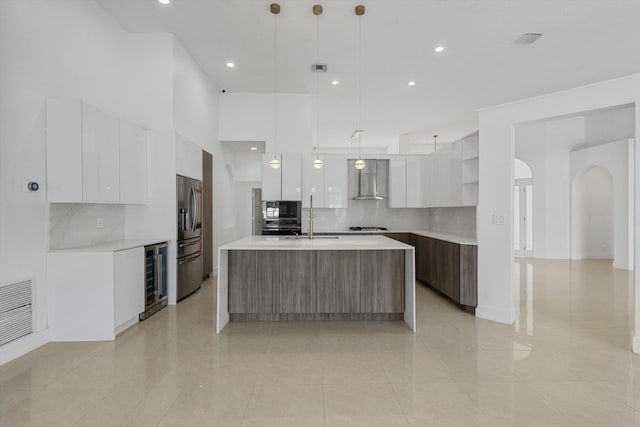 kitchen featuring decorative light fixtures, white cabinetry, a kitchen island with sink, and wine cooler