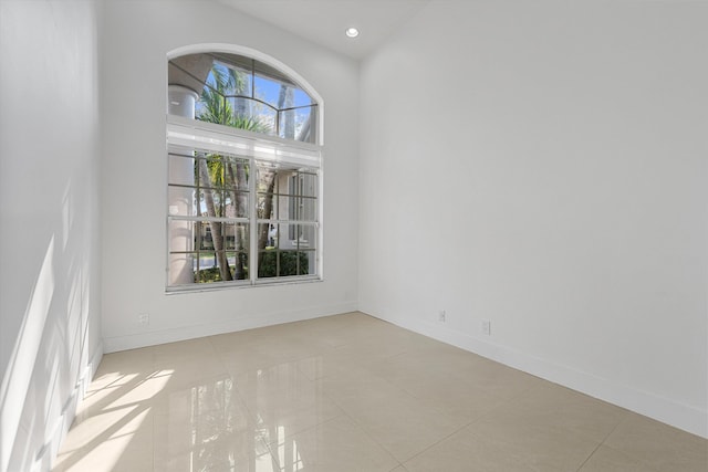 unfurnished room with light tile patterned floors and a high ceiling