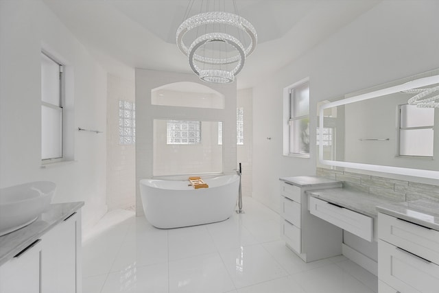 bathroom with a tub to relax in, tile patterned flooring, vanity, and a notable chandelier