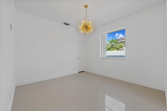 tiled spare room featuring a notable chandelier