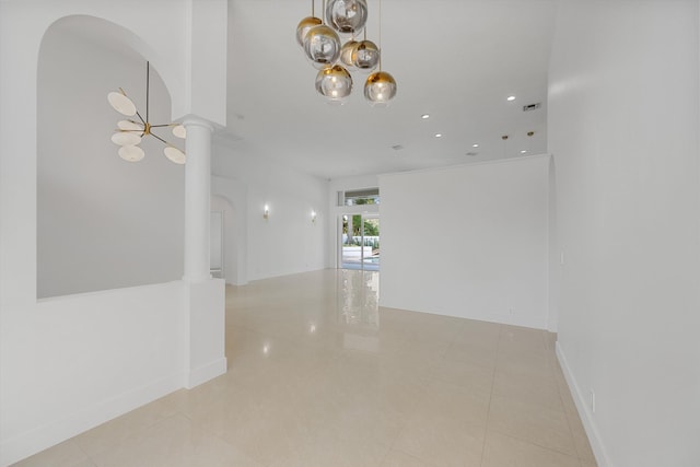 hall featuring decorative columns, light tile patterned floors, and a notable chandelier