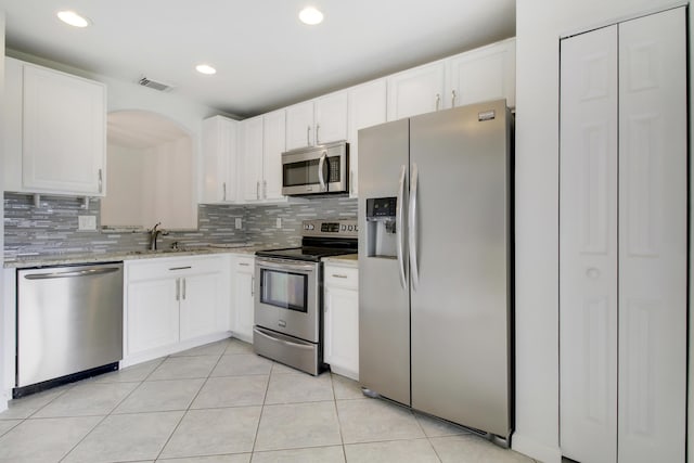 kitchen featuring white cabinets, appliances with stainless steel finishes, light tile patterned floors, and sink