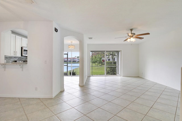 tiled spare room with ceiling fan and a water view