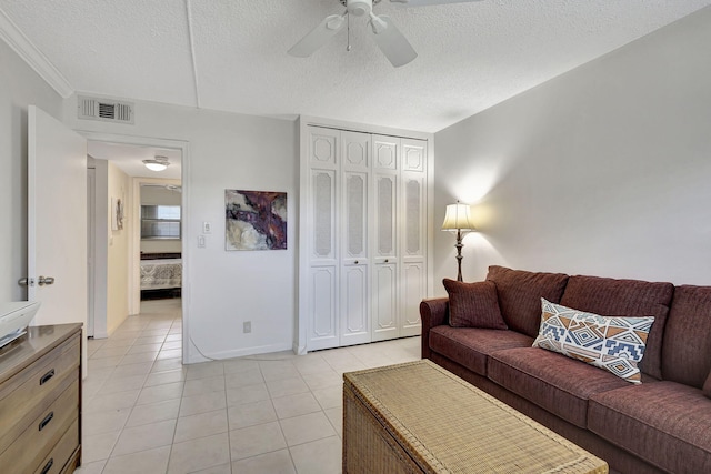 tiled living room with a textured ceiling, ceiling fan, and ornamental molding