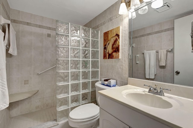 bathroom featuring walk in shower, vanity, toilet, and tile walls