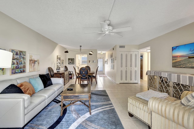 living room featuring ceiling fan, light tile patterned floors, and a textured ceiling